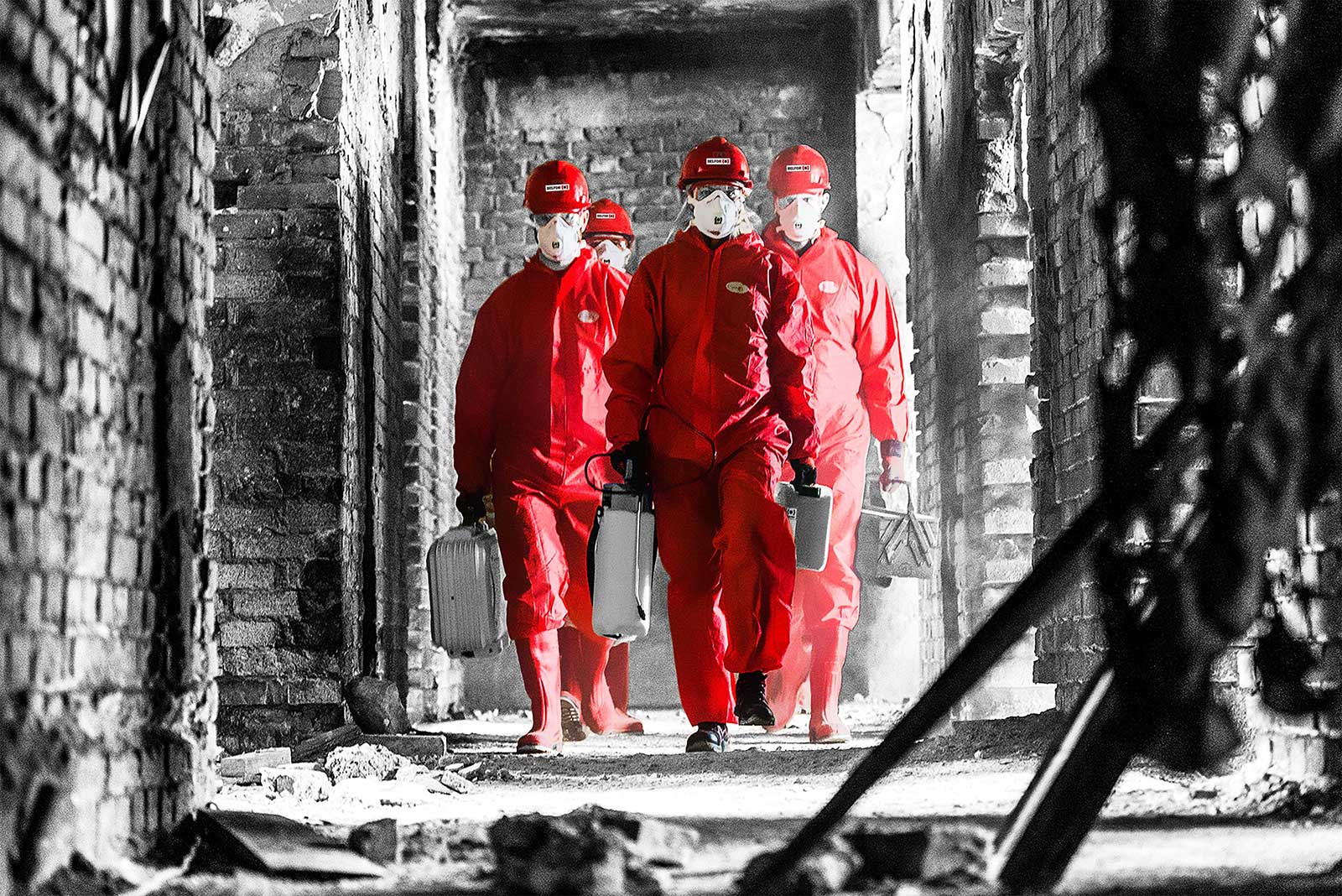 Fyra personer i röd skyddsutrustning går i en korridor