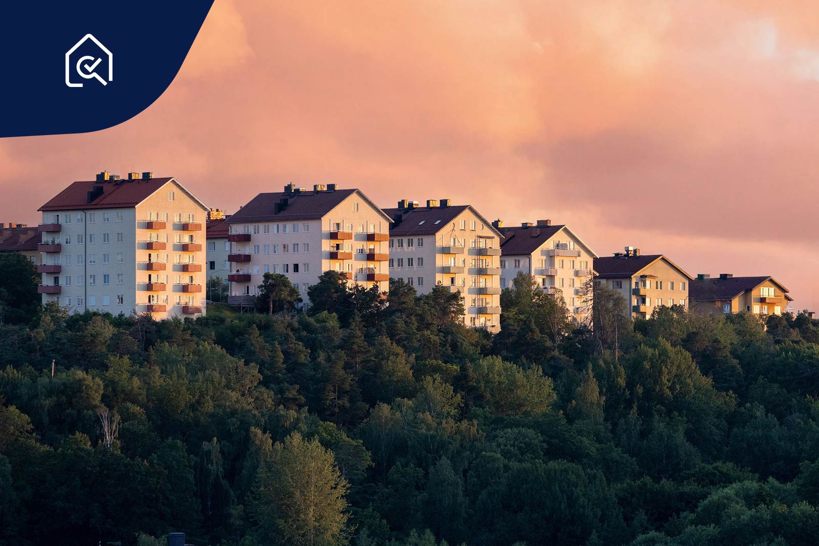 Höghus med bostadsrätter på en grön kulle vid vattnet.