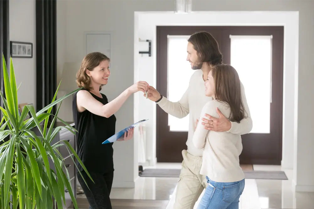 Kvinna lämnar över nycklar till par som ska hyra lägenhet i andrahand.