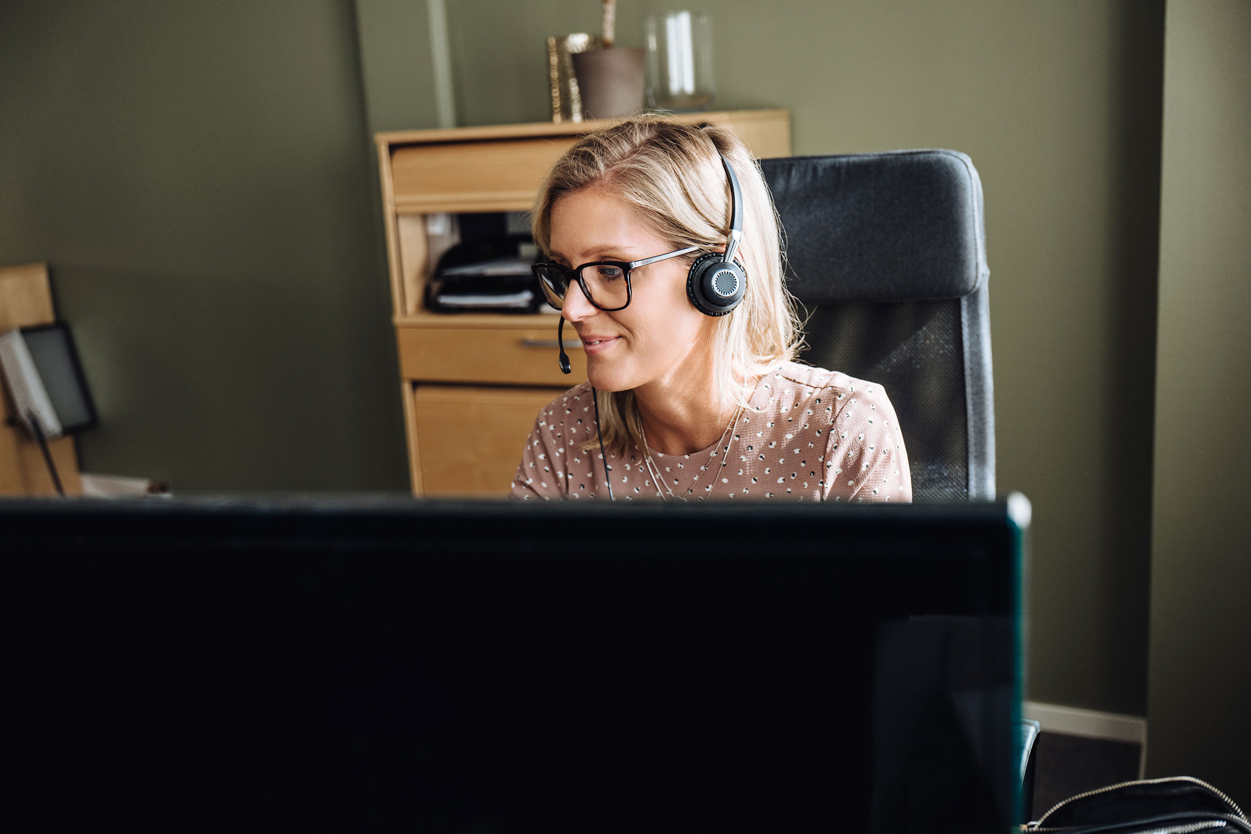 Kuntjänstmedarbetare med headset framför dator
