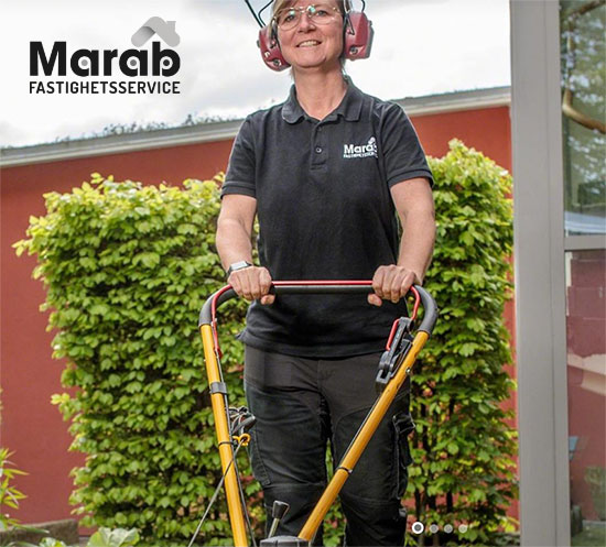 Kvinnlig fastighetsskötare som klipper gräs