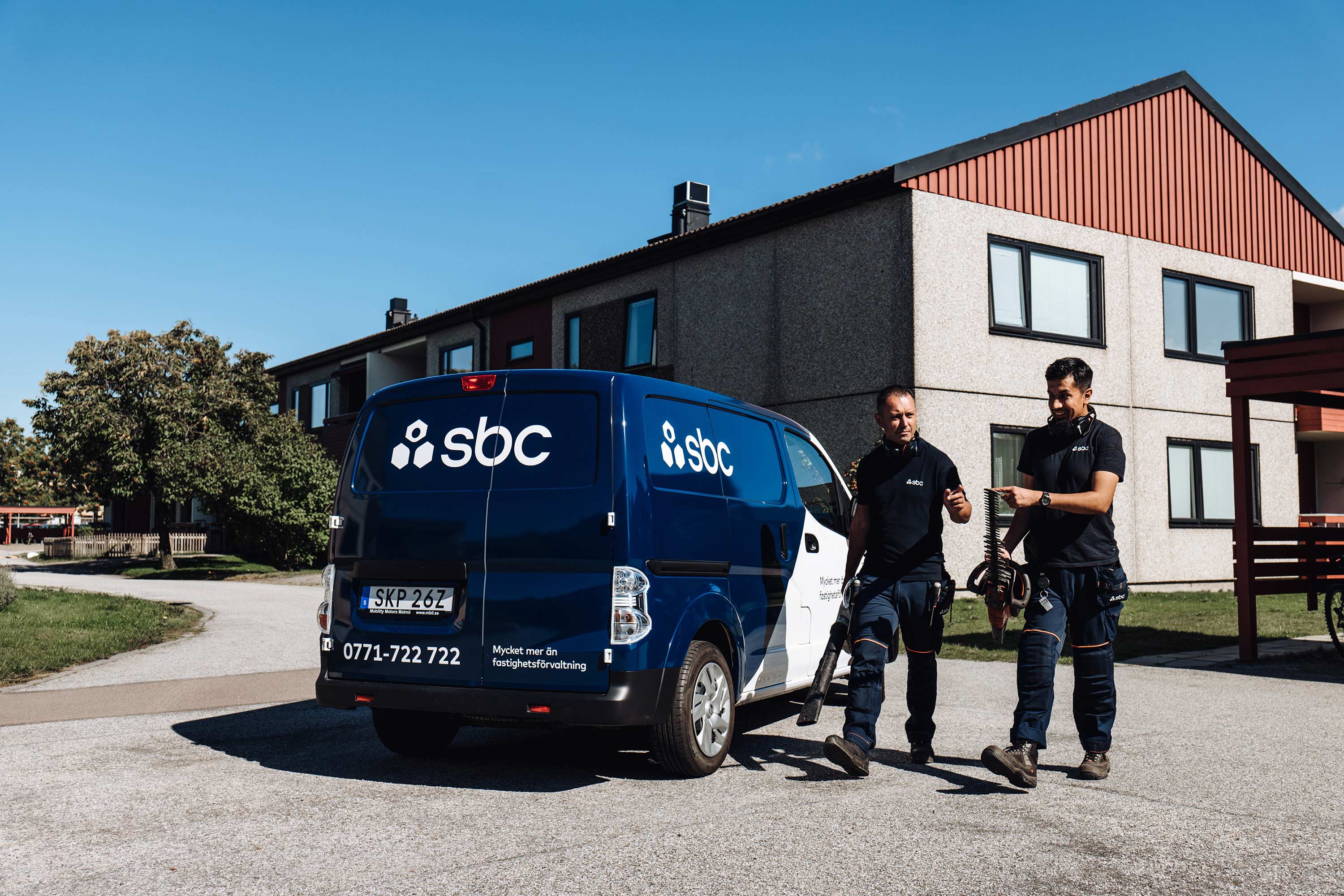 Två fastighetsskötare från SBC bär på trädgårdsredskap
