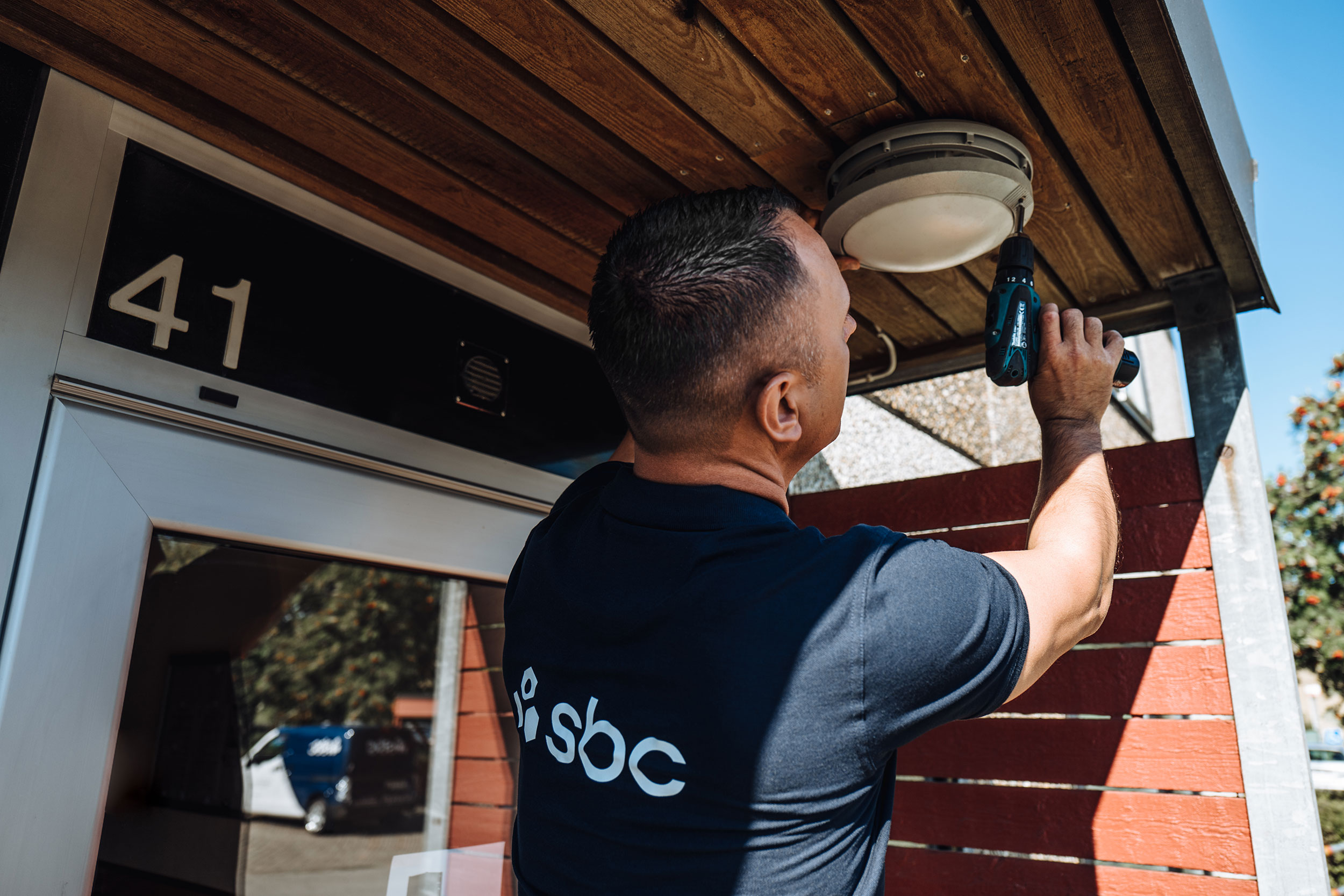 Fastighetsskötare byter lampa utanför brf:s entré