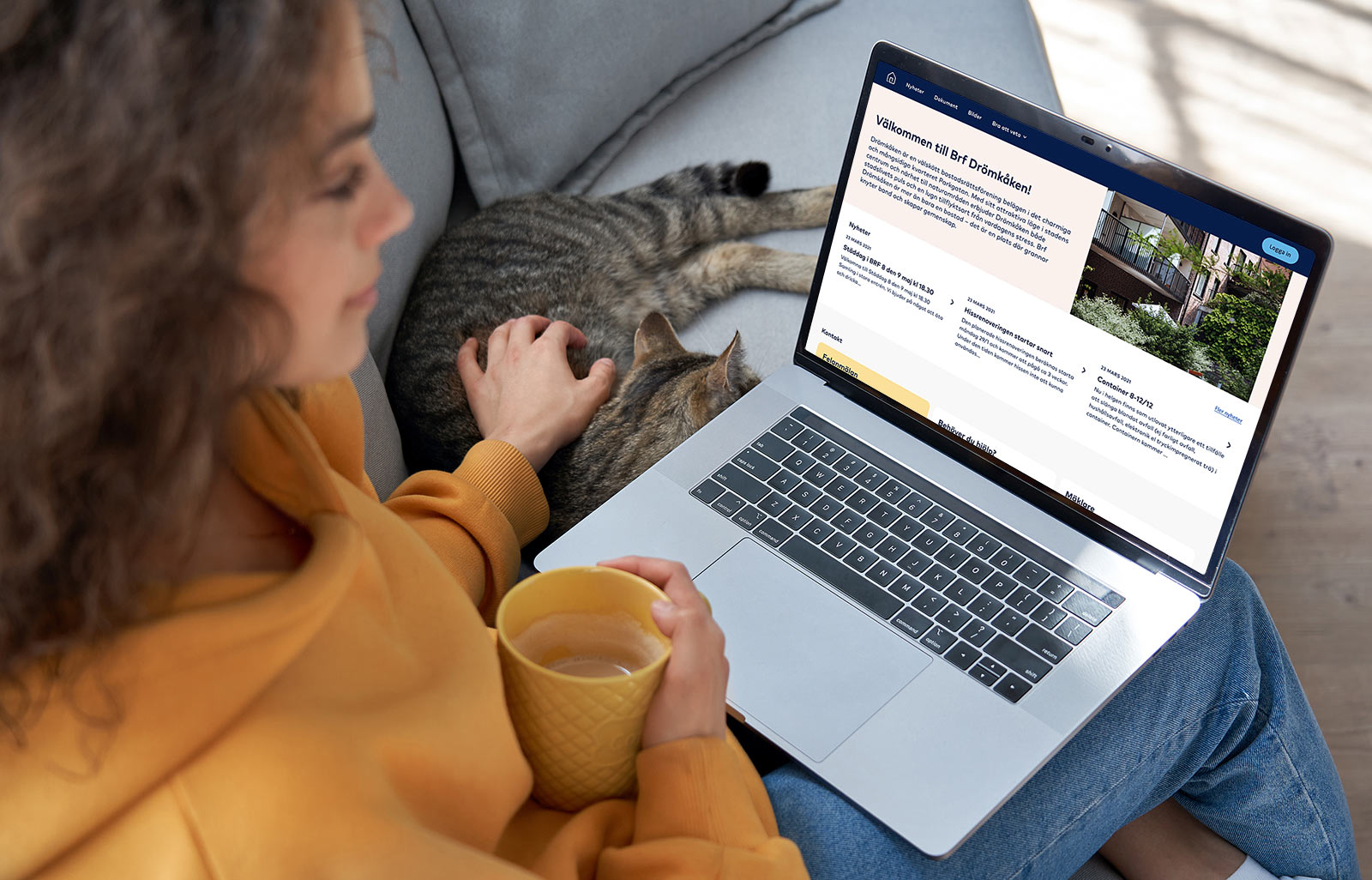 Kvinna sitter i soffan tillsammans med en katt och sin laptop i knät